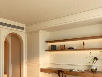 Minimalist bedroom with beige walls, wooden floor, and a desk with shelves.