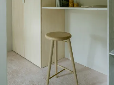 A minimalist home office setup with a wooden desk and stool.