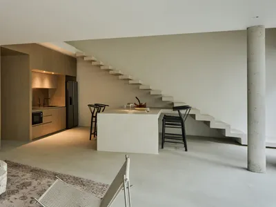 A minimalist residential kitchen with a concrete countertop and a sleek, modern design.