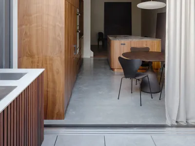 Modern kitchen featuring wooden cabinets and table with a hanging lamp.