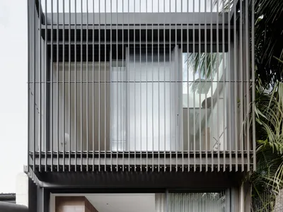 Modern minimalist entryway featuring a kitchen with metal framing, glass curtains, and concrete flooring.