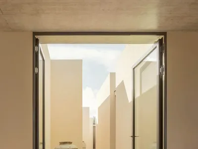 Modern bedroom with neutral colors, concrete walls, wooden floor, and concrete furniture
