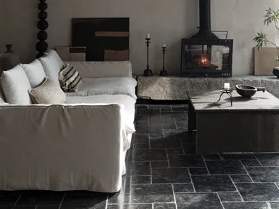 A cozy industrial living room with a concrete fireplace, wooden coffee table, and minimalist decor.