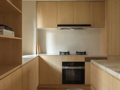 Modern kitchen with minimalist wooden cabinets, countertops, and flooring.