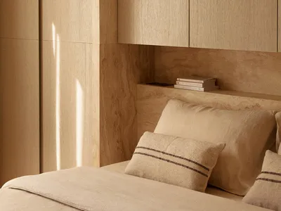 Minimalist bedroom with wooden paneled walls and beige bedding.