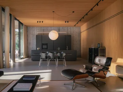 A modern living room featuring black metal kitchen cabinets and wood-textured walls and ceiling.