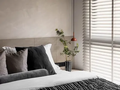 A neatly made bed with a modern minimalist design, featuring a wooden headboard, white bedding, and a green plant in a vase o