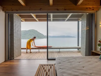 A modern hotel room featuring wooden furniture and a sea view.