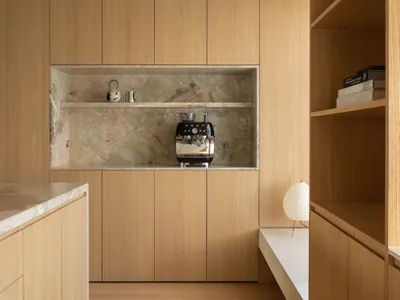 Modern minimalist residential kitchen featuring wooden cabinets and a marble backsplash.