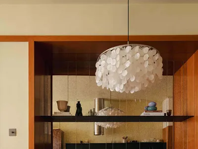 Modern kitchen with a round marble dining table, black furniture, and a chandelier.