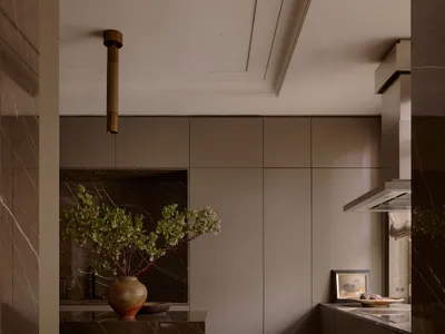 Modern kitchen with marble countertops, wood flooring, and minimalist design.