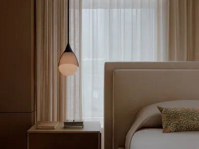 A view of a modern minimalist bedroom with a focus on natural light through sheer curtains and a large window.