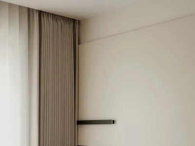 A minimalist bedroom featuring fabric curtains and a leather headboard with a side table and books.