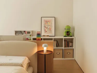 A modern bedroom featuring white walls, a beige sofa, and a wooden floor.