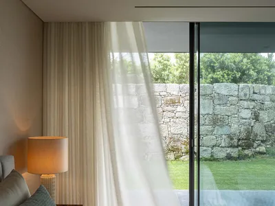 A modern bedroom featuring curtains and minimalist design.