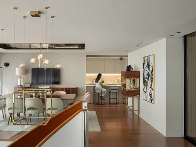 Modern living, dining, and kitchen area featuring wooden floors, glass tables, and metal furniture.