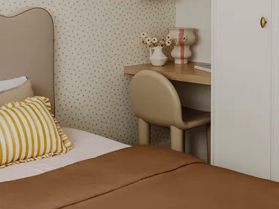 A minimalist bedroom with a bed featuring a neutral-toned fabric and a striped pillow, a desk with a vase of flowers and a la