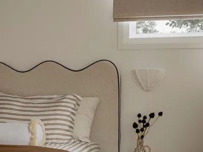 A modern minimalist bedroom with a comfortable bed and a unique nightstand.