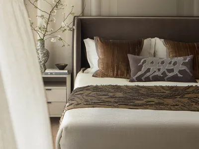 Minimalist bedroom with a bed, pillows, and a vase of flowers on a side table.