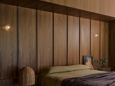 A modern minimalist bedroom featuring wooden paneling, a bed with a wooden platform, and soft lighting.