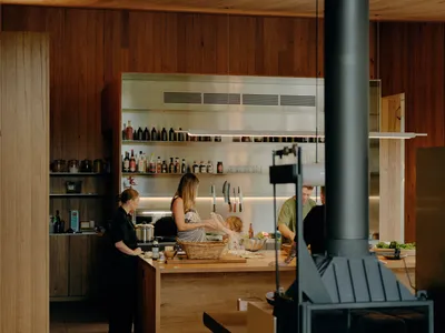 A modern kitchen with wooden elements and a family cooking together under a wooden ceiling.