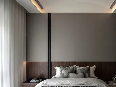 A stylish, minimalist bedroom with a bed against a large, wooden-walled backdrop, featuring grey and white bedding and decora