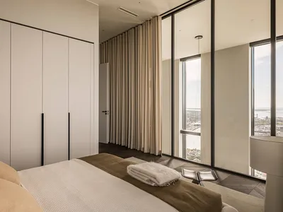 Contemporary bedroom with neutral tones and large windows overlooking a scenic view.