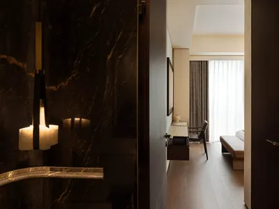 A modern hotel room showcasing marble walls and wooden flooring.