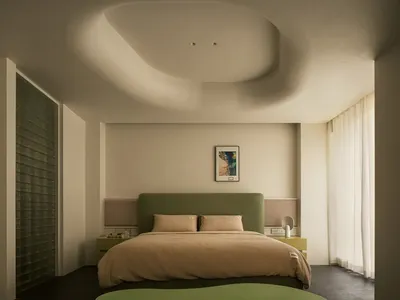 A minimalist bedroom with a green fabric headboard and a glass window