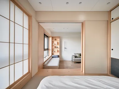 A minimalist bedroom featuring wood furnishings, fabric bedding, and plaster walls.
