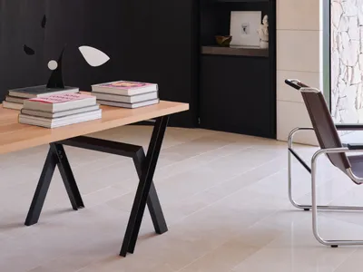 A modern, minimalist home office featuring a black metal and wood desk with books and a lamp, alongside a sleek, minimalist a