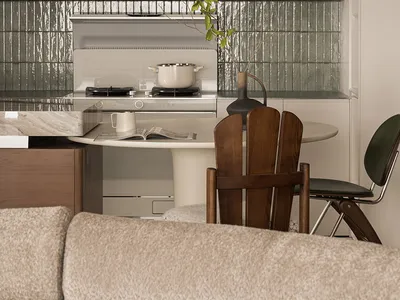 Modern residential kitchen with marble countertops and stainless steel appliances viewed from a comfortable seating area.