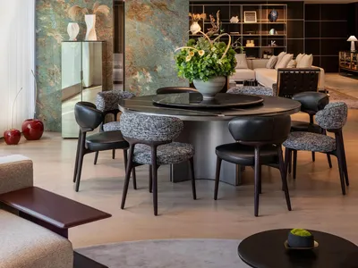 Contemporary living room with a round marble table, leather chairs, and a wooden floor.