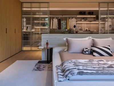 Modern minimalist bedroom with monochromatic color scheme and visible closet system.