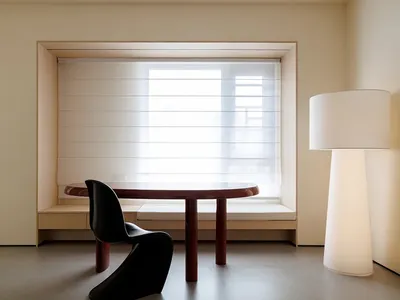 A modern home office featuring wood furniture, a round table, and a black chair, with a large window and a floor lamp.