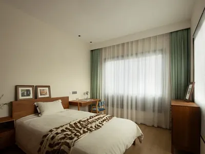 Modern minimalist bedroom with wooden furniture and glass windows.