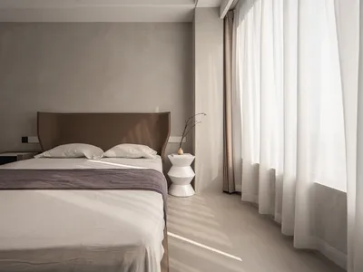 Modern minimalist bedroom featuring a sleek white bed with a glass and metal headboard, clean lines, and a cozy atmosphere cr