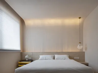 Modern minimalist bedroom featuring a wooden headboard and white blinds.