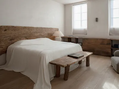 A minimalist bedroom featuring a wooden bed with a textured wooden headboard and a matching wooden bench.