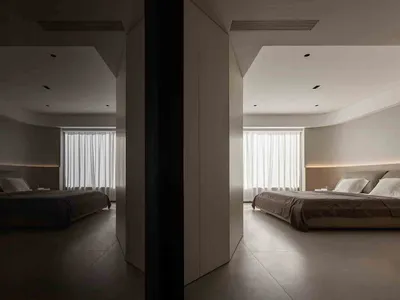 A minimalist bedroom with neutral tones, white curtains, and a simple bed.