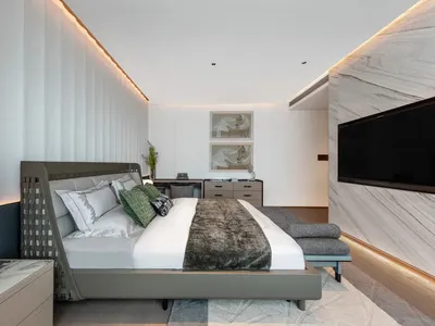 A minimalist bedroom with a modern design, featuring a large bed, white walls, and a marble-like accent wall.