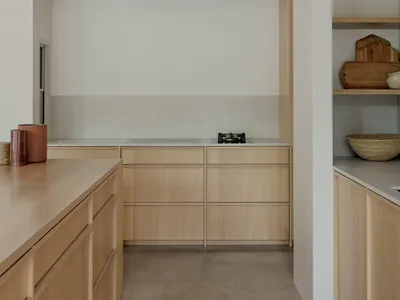 Modern minimalistic kitchen featuring concrete flooring and wood cabinetry.