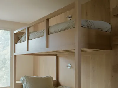 A modern wooden bunk bed with a light blue mattress and pillows.