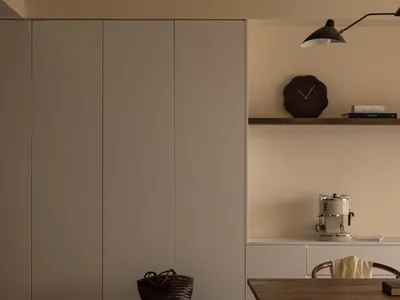 A minimalist kitchen with white-painted board cabinetry and a wooden table with chairs.