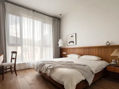 A minimalist bedroom featuring wooden furniture and a bed with white bedding and a wood headboard.