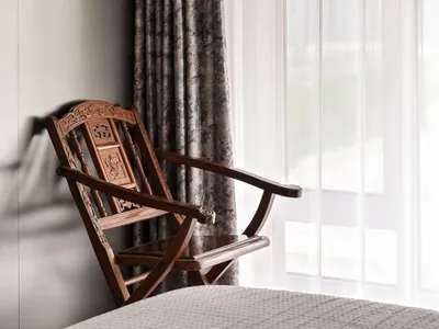 A minimalist bedroom featuring a wooden chair by a window.