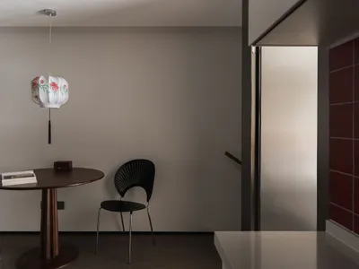 A minimalist residential kitchen featuring wood elements and a round wooden table with a circular pendant light fixture hangi