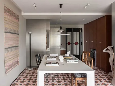 Modern home office with concrete flooring, white desk, black chairs, and minimalist design.