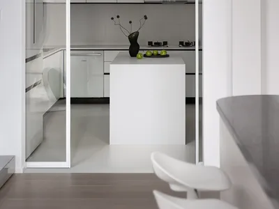 White minimalist kitchen with white cabinets, black accents, and a white island.
