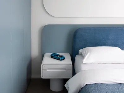 Minimalist bedroom with a blue tiled accent wall, white walls, and white floor.